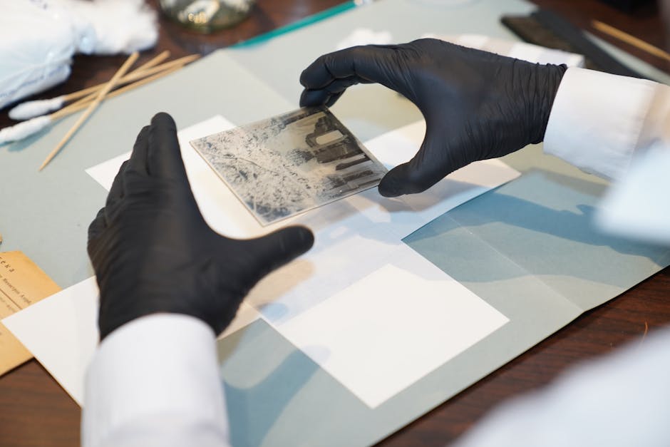 A specialist restoring an old photo using gloves and tools for careful preservation.