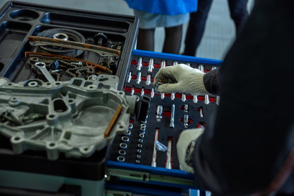 A mechanic in gloves organizing engine parts and tools in a workshop setting.